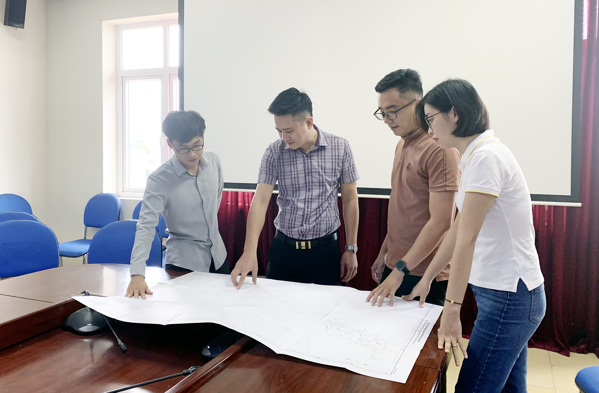 Cán bộ Trung tâm Phát triển quỹ đất huyện Vân Đồn bàn phương án thực hiện GPMB các dự án trên địa bàn. Ảnh: Mạnh Trường