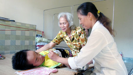 Nhân viên Trung tâm Bảo trợ xã hội giúp bà Thảo chăm sóc con gái.