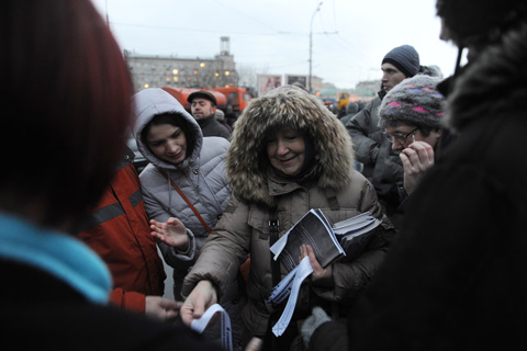 Một phụ nữ phát các dải ruy băng trắng, biểu tượng của phong trào đối lập, cho những người tham gia biểu tình chống đảng Nước Nga Thống nhất hôm 10/12 ở Moscow. Ảnh: NY Times