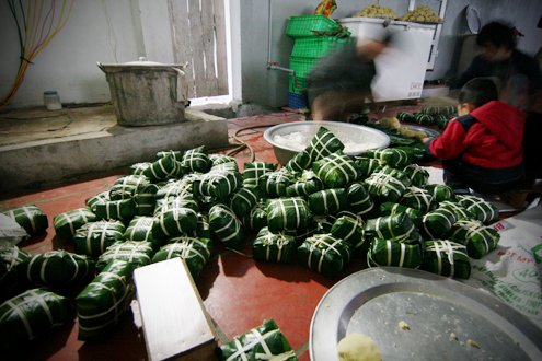 After the wrapping stage, banh chung are boiled in big pots for eight hours. After that the cakes are washed by cold water and pressed by heavy things.