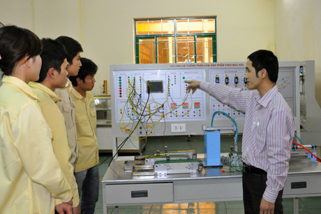 Thầy giáo Lê Thanh Tình (bên phải) hướng dẫn sinh viên kết nối mô hình hệ thống tự đếm và phân loại sản phẩm theo màu sắc.