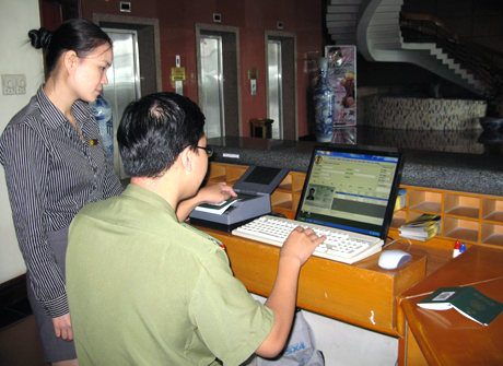 Cán bộ  Phòng QLXNC Công an tỉnh, hướng dẫn nhân viên Khách sạn Sài Gòn Hạ Long sử dụng máy đọc thông tin từ hộ chiếu vào máy tính.