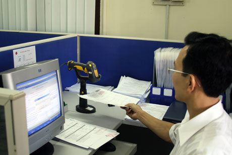 Cán bộ ngành thuế sử dụng máy quét mã vạch kiểm tra hồ sơ hoá đơn, chứng từ. Ảnh: Thu Trang