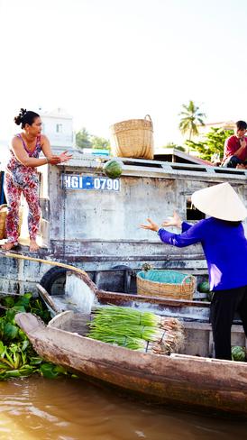 The relatively peaceful floating market of Cai Rang at early dawn.  Traders carry watermelons, pineapples and beets to small boats.
