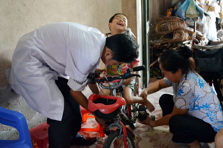 Bác sĩ của Trung tâm Y tế TX Quảng Yên phối hợp với gia đình hướng dẫn kỹ thuật tập phục hồi chức năng cho bé Đại Nam.
