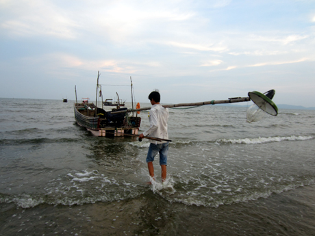 Anh Nguyễn Văn Nhiêm vác cột đèn cao áp (đồ nghề không thể thiếu của người câu mực) ra bè, chuẩn bị khởi hành chuyến câu đêm.