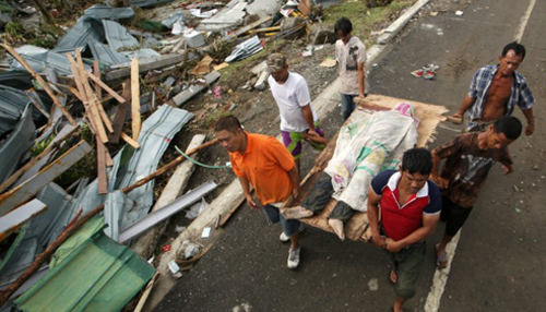 Người sống sót khiêng một xác người chết trong khung cảnh tiêu điều ở Tacloban. Ảnh: CNN