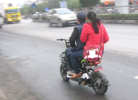 Học sinh không đội mũ bảo hiểm khi đi xe đạp điện tham gia giao thông (ảnh chụp tại cổng trường THPT Hòn Gai ).