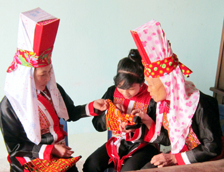 Nghệ nhân dân gian Diềng Chống Sếnh (bên phải) hướng dẫn cho lớp trẻ những mũi kim thêu đầu tiên