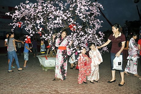 Người dân, du khách chụp ảnh bên hoa anh đào tại lễ hội.
