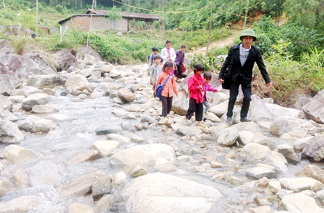 Thầy giáo Vi Văn Trình đưa những học trò nhỏ lội suối đến với điểm trường Tiểu học Sông Moóc B.