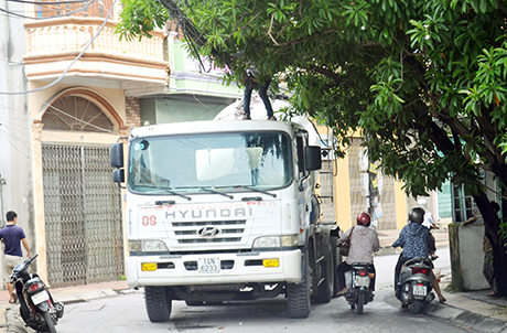 Xe đổ bê tông bị vướng dây điện thoại trên đường, phụ xe phải leo lên gỡ. (Ảnh chụp lúc 8 giờ ngày 4-8-2014 tại đường Cẩm Bình, phường Cẩm Bình, TP Cẩm Phả). 
