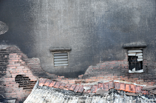Tường của các nhà dân xung quanh bị bong tróc, bám đầy khói đen.