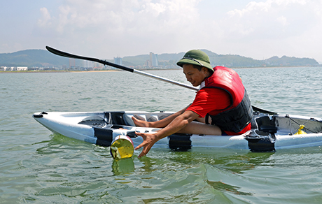 Thành viên của CLB Kayak Hạ Long vừa luyện tập chèo thuyền, vừa thu gom rác thải trên mặt Vịnh.