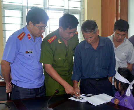 Đại diện gia đình anh Nguyễn Văn Sửu xem bản ảnh hiện trường tử thi và vật chứng thu giữ