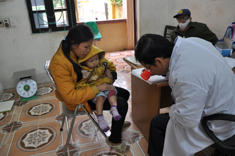 bác sỹ Trạm y tế xã Vô Ngại (Bình Liêu) kiểm tra vết bỏng ở chân cho một em bé bản Ngày II.