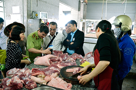 Đoàn kiểm tra liên ngành VSATTP của tỉnh thực hiện kiểm nghiệm nhanh mẫu thịt tại chợ Hồng Hà, TP Hạ Long. (ảnh chụp ngày 23-4-2015)