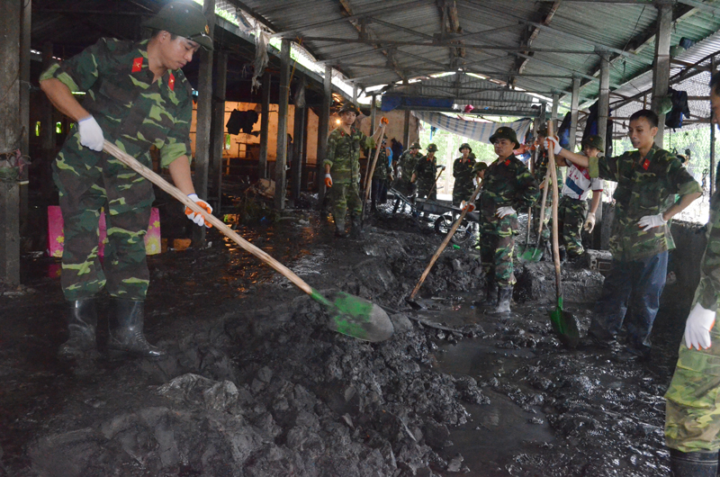Cán bộ, chiến sĩ Công ty TNHH MTV Khai thác khoáng sản (Tổng Công ty Đông Bắc) giúp dân nạo vét bùn ở chợ Hà Phong.