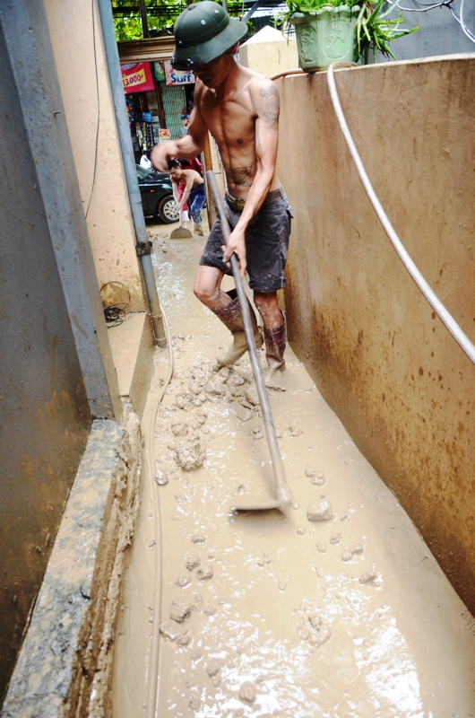 Người dân khu 1 phường Hà Khách đang thu dọn lượng bùn đất đổ vào nhà do tình trạng sạt lở tái diễn
