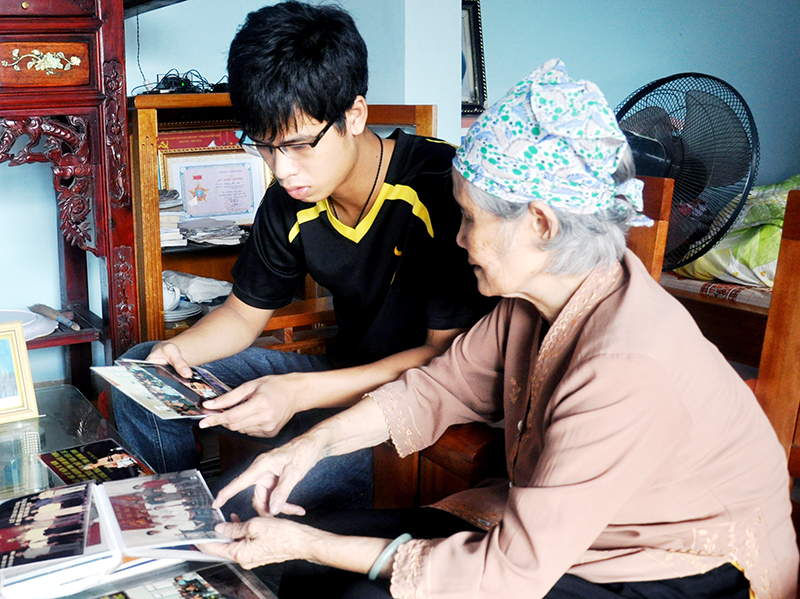 Bà Hoàng Thị Mùi kể lại cho cháu nội về những lần gặp gỡ đồng đội năm xưa.