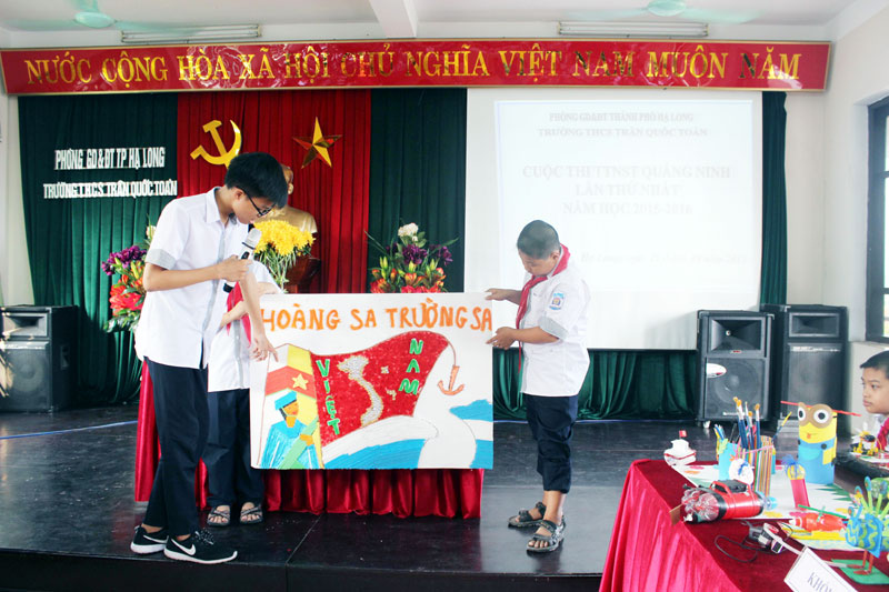 Ngô Minh Tân (bên trái), lớp 9A1, Trường THCS Trần Quốc Toản (TP Hạ Long) giới thiệu về sản phẩm “Tranh biển đảo quê hương từ phế liệu”. (Ảnh: Trường THCS Trần Quốc Toản cung cấp)