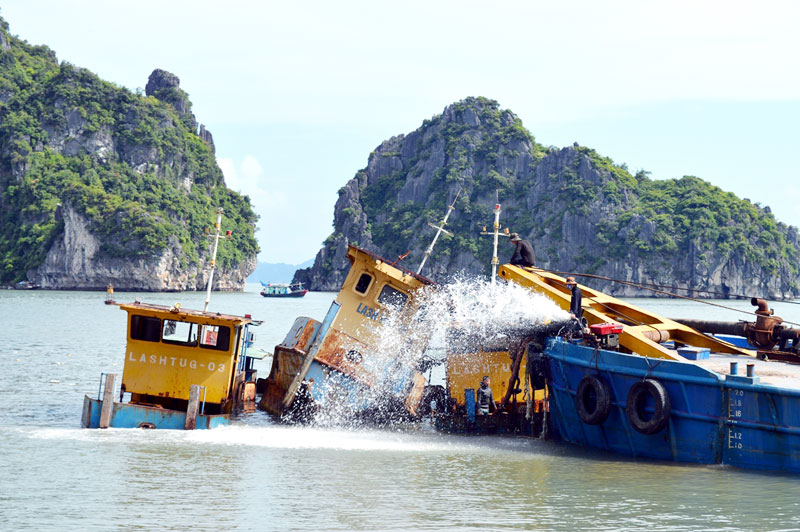 Công nhân Công ty TNHH MTV Vận tải Viễn Dương Vinashin bơm nước để làm nổi tàu trước khi trục vớt. (Ảnh chụp ngày 7-6-2016)