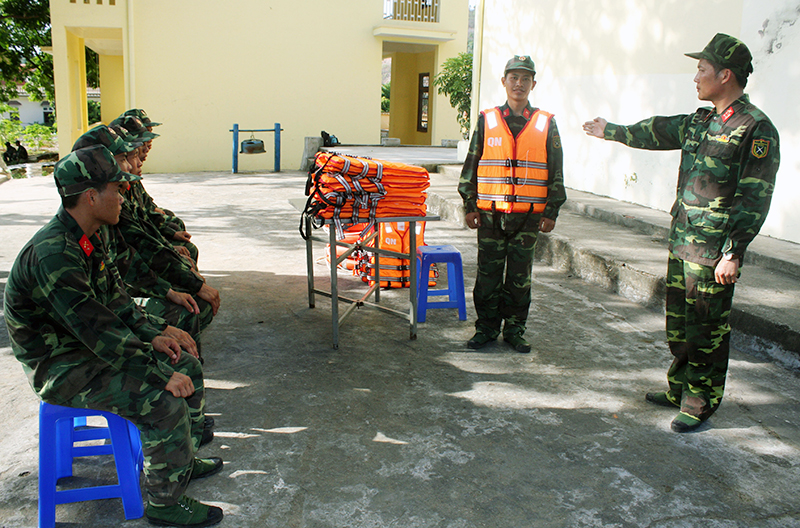 Đại uý Bùi Văn Dưỡng (ngoài cùng, bên phải) giới thiệu quy cách mang, sử dụng áo phao, phao tròn khi tham gia tìm kiếm cứu nạn cho cán bộ, chiến sĩ đơn vị.