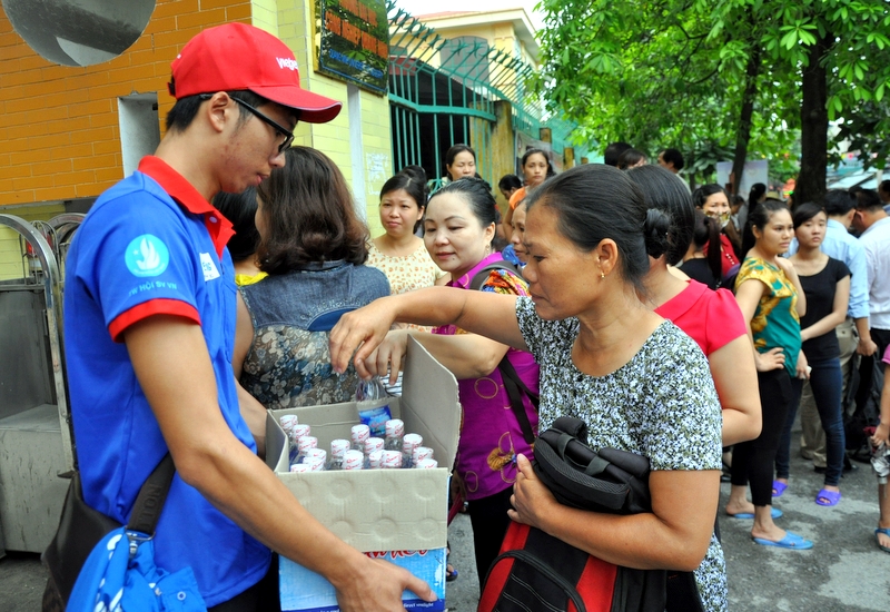 Tình nguyện viên phát nước miễn phí cho phụ huynh thí sinh bên ngoài khu vực thi tại Điểm thi Trường ĐH Công nghiệp Quảng Ninh.
