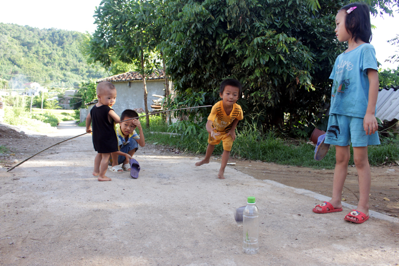 Bố mẹ bận mưu sinh, trẻ em ở thôn Chang Nà, xã Tình Húc, phải tự trông nhau và bày những trò chơi ngay tại đường giao thông.