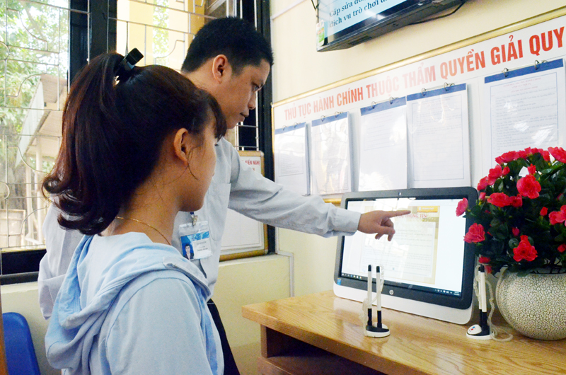 Cán bộ bộ phận “Một cửa điện tử hiện đại” phường Cẩm Tây (TP Cẩm Phả) hướng dẫn người dân tra cứu thông tin qua hệ thống điện tử.