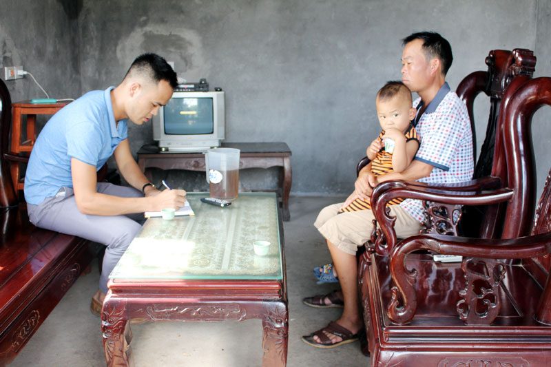 Cán bộ xã Vô Ngại (bên trái) trao đổi với anh Đinh Văn Tầu, thôn Nà Cắp, xã Vô Ngại để hoàn thiện hồ sơ đề nghị hỗ trợ theo Nghị quyết số 222/2015/NQ-HĐND của HĐND tỉnh cho hai con của anh là Đinh Đình Tùng và Đinh Thị Xoan.