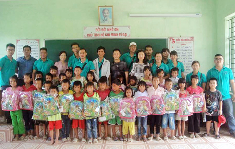 Các thành viên CLB Thiện nguyện Cửa Ông tặng cặp sách cho các em học sinh nghèo tại điểm trường Lý Là, Trường Tiểu học xã Quảng Đức (huyện Hải Hà).