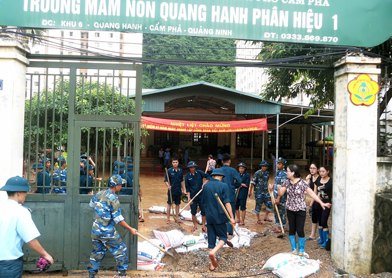 Cán bộ, giáo viên và lực lượng bộ đội tham gia khắc phục ngập lụt tại phân hiệu I Trường Mầm non Quang Hanh sau trận mưa ngày  21-7-2016.