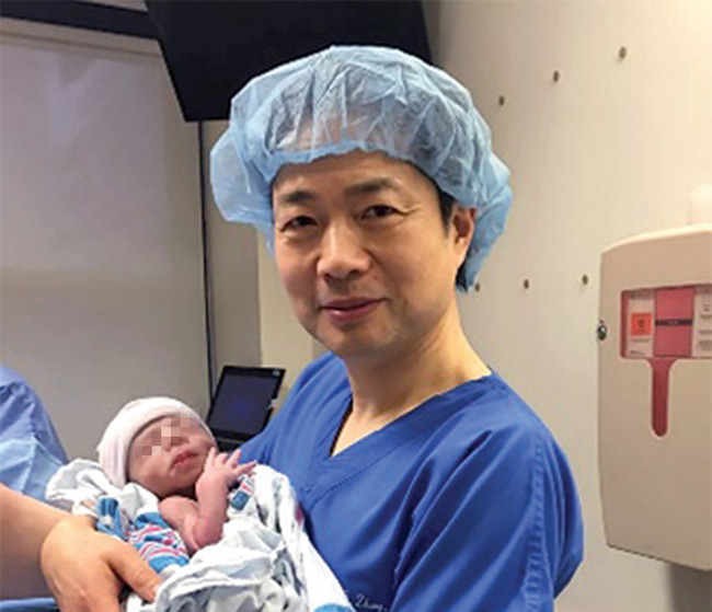 Tiến sĩ John Zhang đang ẵm em bé. (Ảnh: Newscientist)