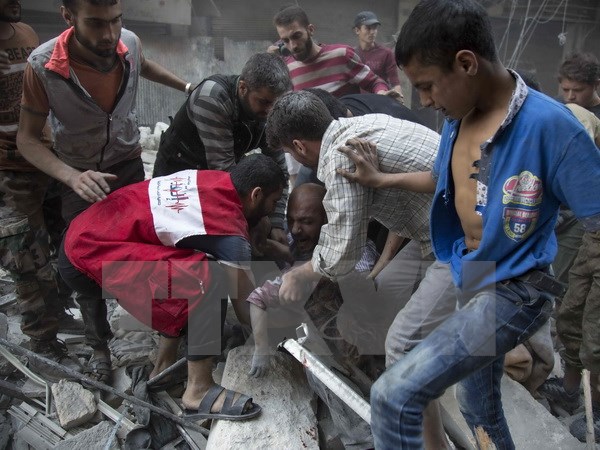Một người đàn ông đau khổ sau khi tìm thấy xác con dưới những đống đổ nát sau các vụ không kích tại Aleppo ngày 27/9. (Nguồn: AFP/TTXVN)