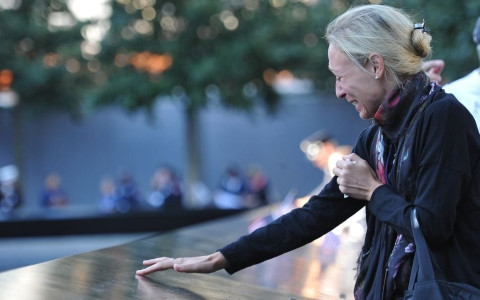 Một thân nhân không kìm được nước mắt khi chạm tay vào tên người thân của mình tại Đài tưởng niệm các nạn nhân vụ 11/9. Ảnh: AP