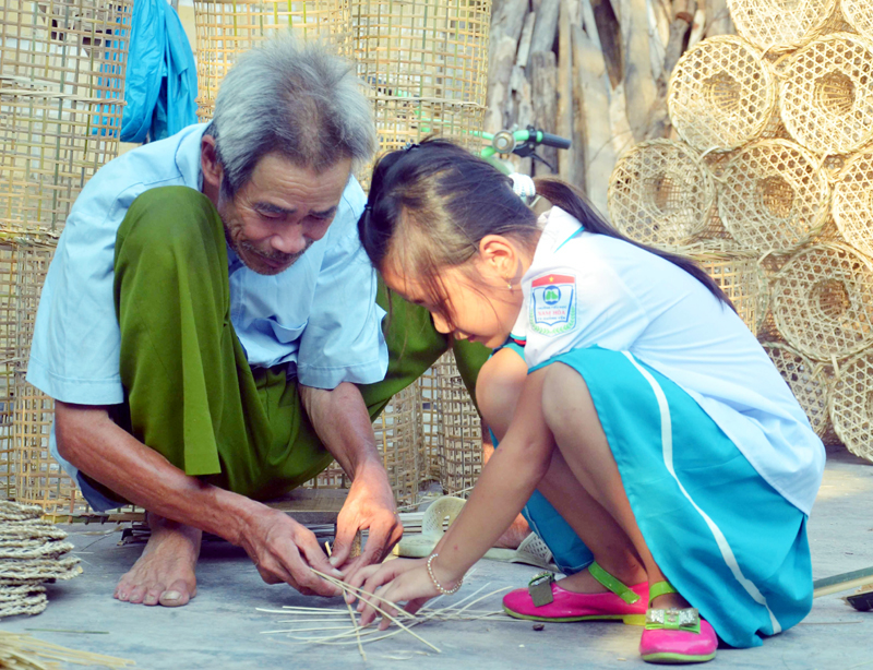 Nghệ nhân Đặng Quang Thuân dạy cháu nội đan lát.