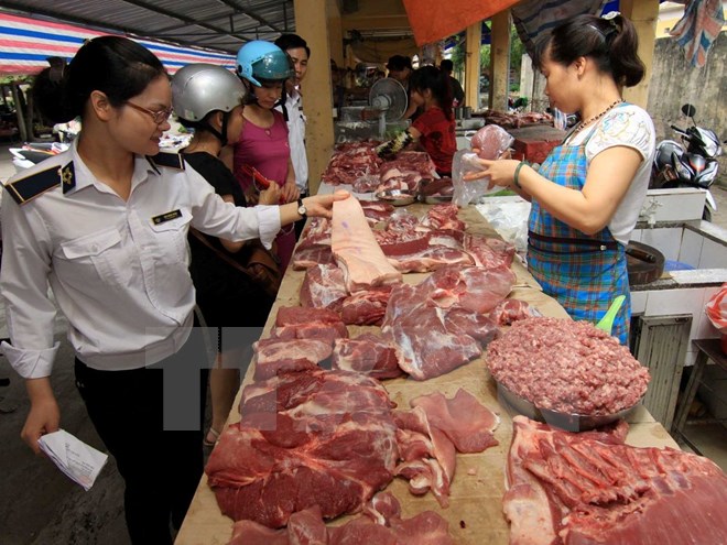 Nhân viên thú y kiểm tra hộ kinh doanh thịt lợn tại chợ. (Ảnh: Vũ Sinh/TTXVN)