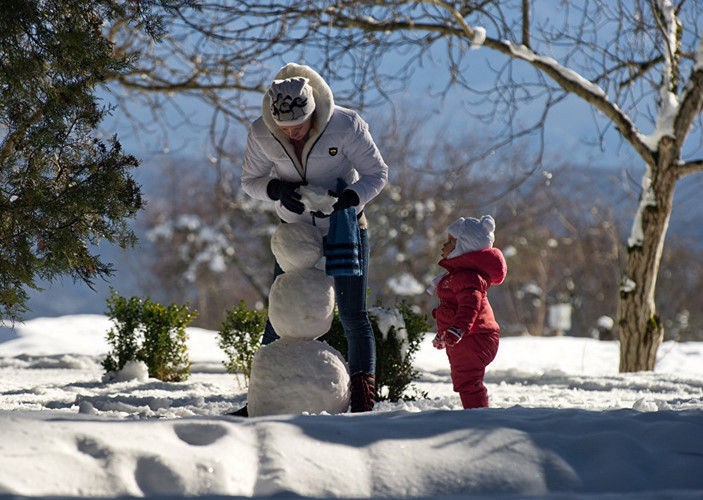   Hai mẹ con đắp hình một chú người tuyết ở khu vực làng Nauchny, huyện Bakhchysaray thuộc Crimea.