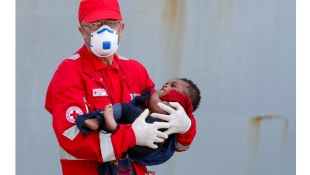 Một nhân viên thuộc Hội Chữ thập đỏ Italia ẵm một trẻ em di cư sau khi rời tàu Hải quân Aviere tại cảng Augusta, Sicilia, Italia, ngày 10-6-2016. (Ảnh: Reuters)