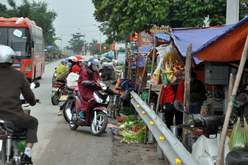 Tại khu vực chợ tạm thuộc thôn 4, xã Quảng Long, hoạt động buôn bán diễn ra ngay bên lề Quốc lộ 18A có nguy cơ mất an toàn giao thông rất cao