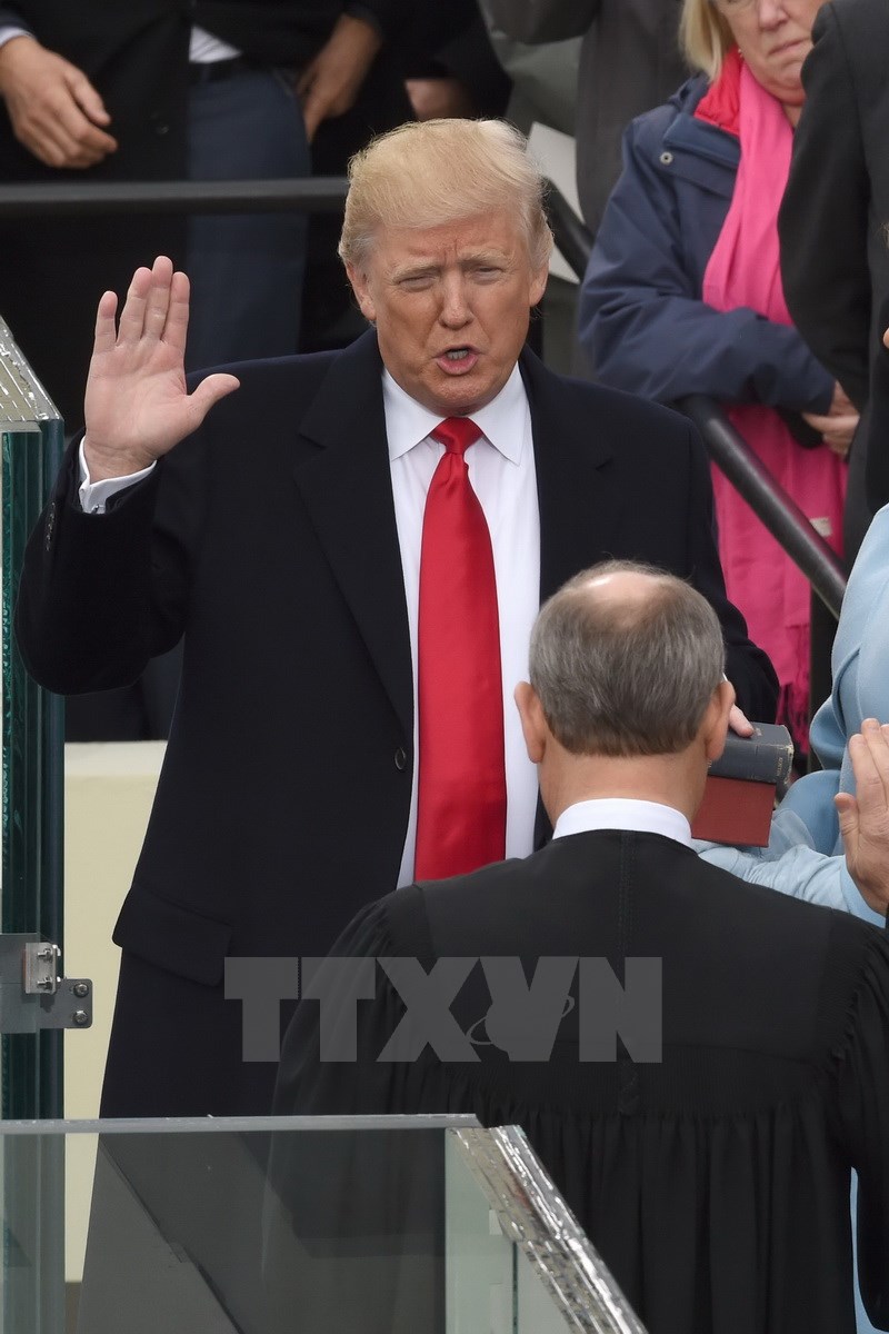 Tổng thống đắc cử Donald Trump (trái) đọc lời tuyên thệ tại Washington, DC, ngày 20/1. (Nguồn: AFP/TTXVN)