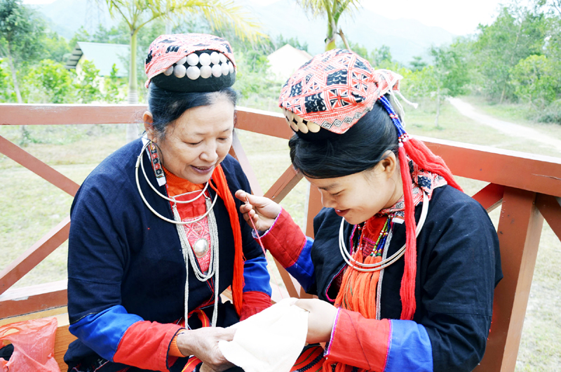 Nghệ nhân Trương Thị Quý hướng dẫn thêu trang phục truyền thống cho chị Bùi Thị Dung (18 tuổi) thôn 2, xã Bằng Cả.