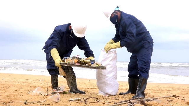 Công nhân đang thu gom dầu vón cục và rác thải trên bãi biển Núi Thành