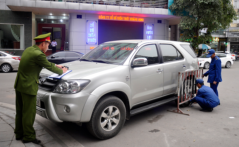 Lực lượng chức năng phường Bạch Đằng lập biên bản để xử lý chủ một xe ô tô đỗ không đúng nơi quy định, phía trước trụ sở Công ty Xổ số kiến thiết Quảng Ninh.