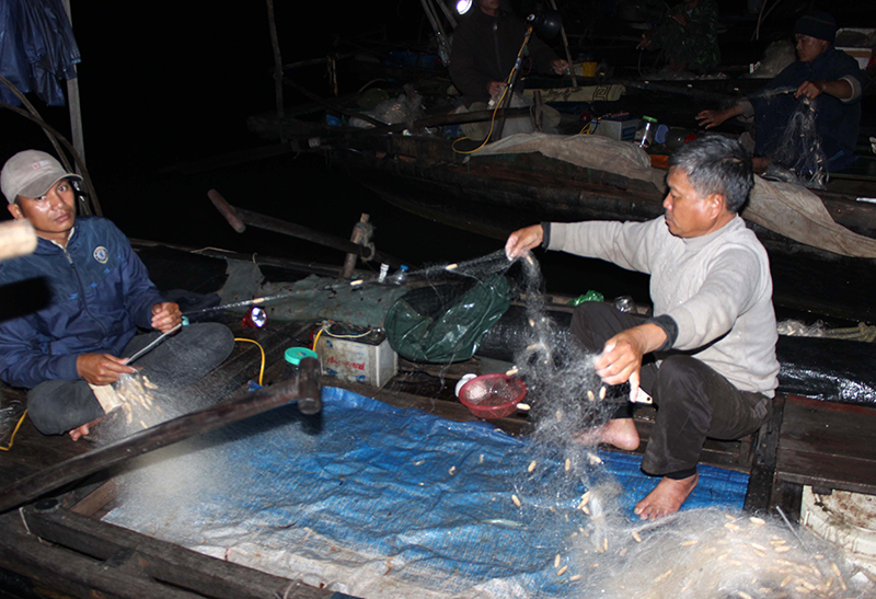 Bán xong cá, ông Đinh Văn Hạnh (bên phải), ở thôn 5, xã Hiệp Hoà và bạn thuyền tranh thủ gỡ lưới chuẩn bị ngày mai lại ra khơi.