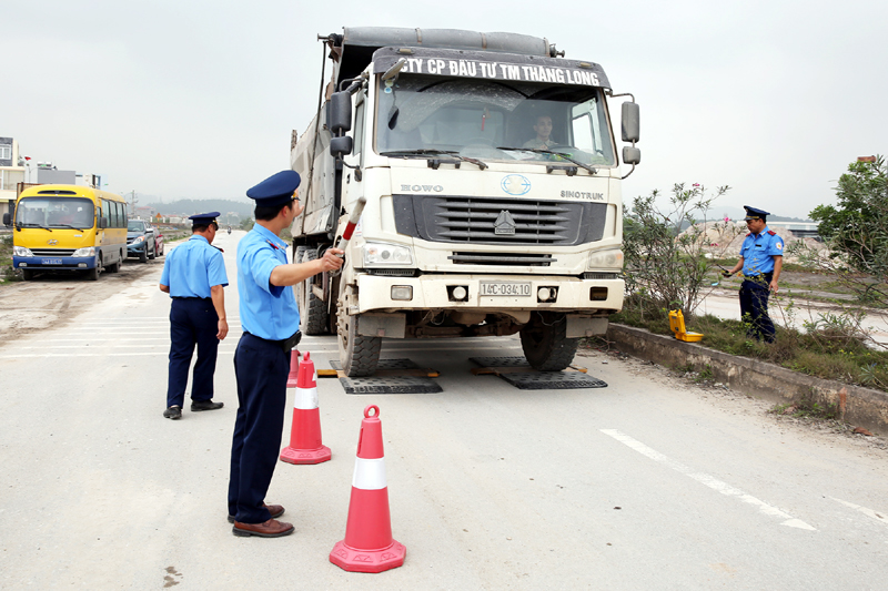 Lực lượng chức năng sử dụng cân xách tay kiểm tra tải trọng xe trên Quốc lộ 18.