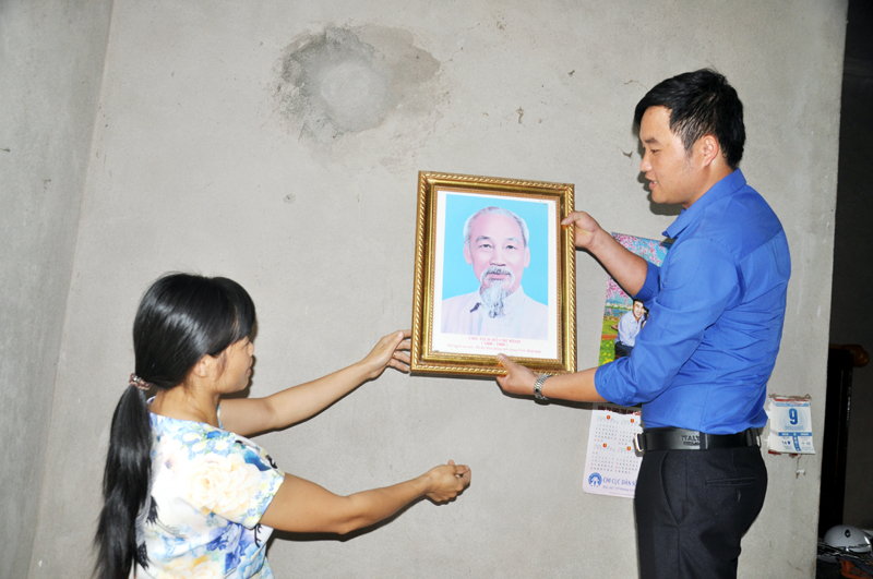 Cán bộ Đoàn Thanh niên xã Tình Húc, huyện Bình Liêu giúp người dân thôn Chang Nà, xã Tình Húc treo ảnh Bác Hồ tại gia đình.