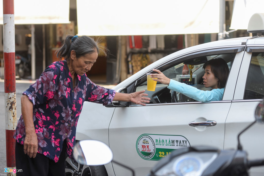 Nữ lái xe taxi tranh thủ ngồi từ trong xe để gọi nước uống giải khát.