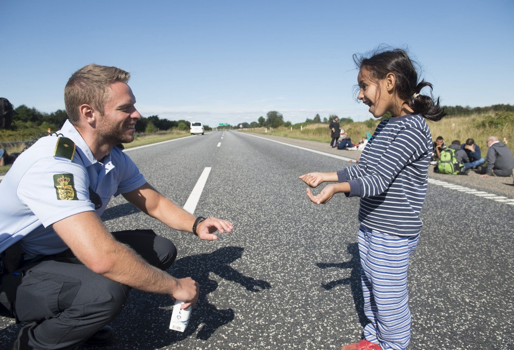 Nam cảnh sát chơi đùa với một cô bé di cư ở Đan Mạch. Ảnh: Claus Fisker/Reuters.